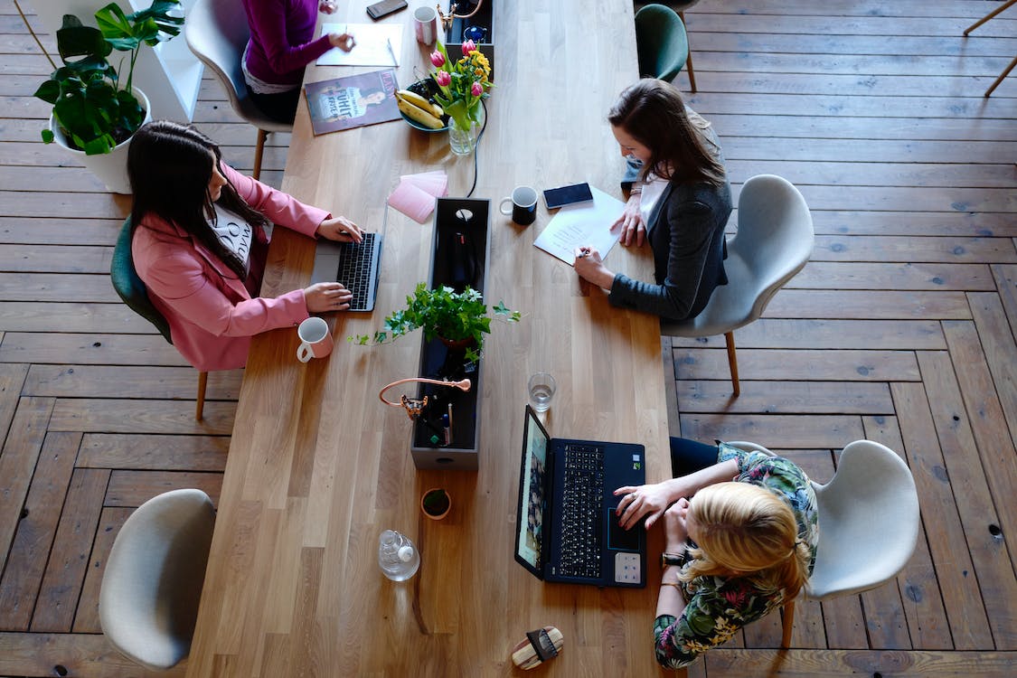 espacios de trabajo mesa compartida hotdesking oficina mujeres portatil plantas mesa madera