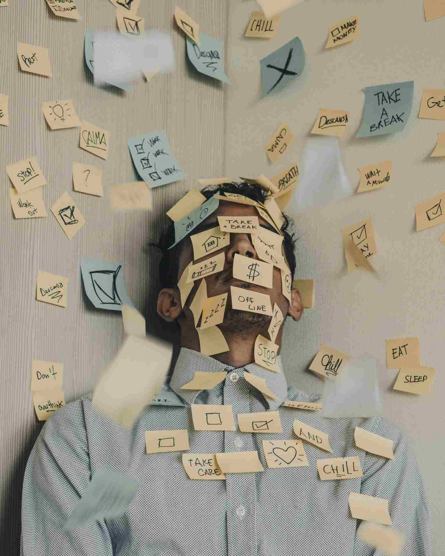 una persona agobiada con el trabajo en la oficina descansa con la cara cubierta de posit con mensajes para despertar su motivacion intrinseca